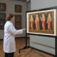 Art conservator using advanced technology for painting analysis in modern conservation lab with digital restoration equipment