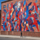 Person stopping to view colorful street art mural demonstrating street